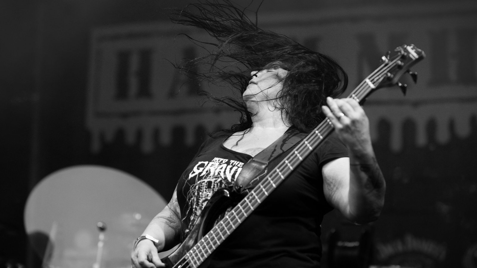 La bassiste Sonja Traussnig d'Urban Grey jouant avec intensité, la tête penchée en arrière et les cheveux fouettant l'air au Hills of Rock 2025 à Plovdiv, en Bulgarie.