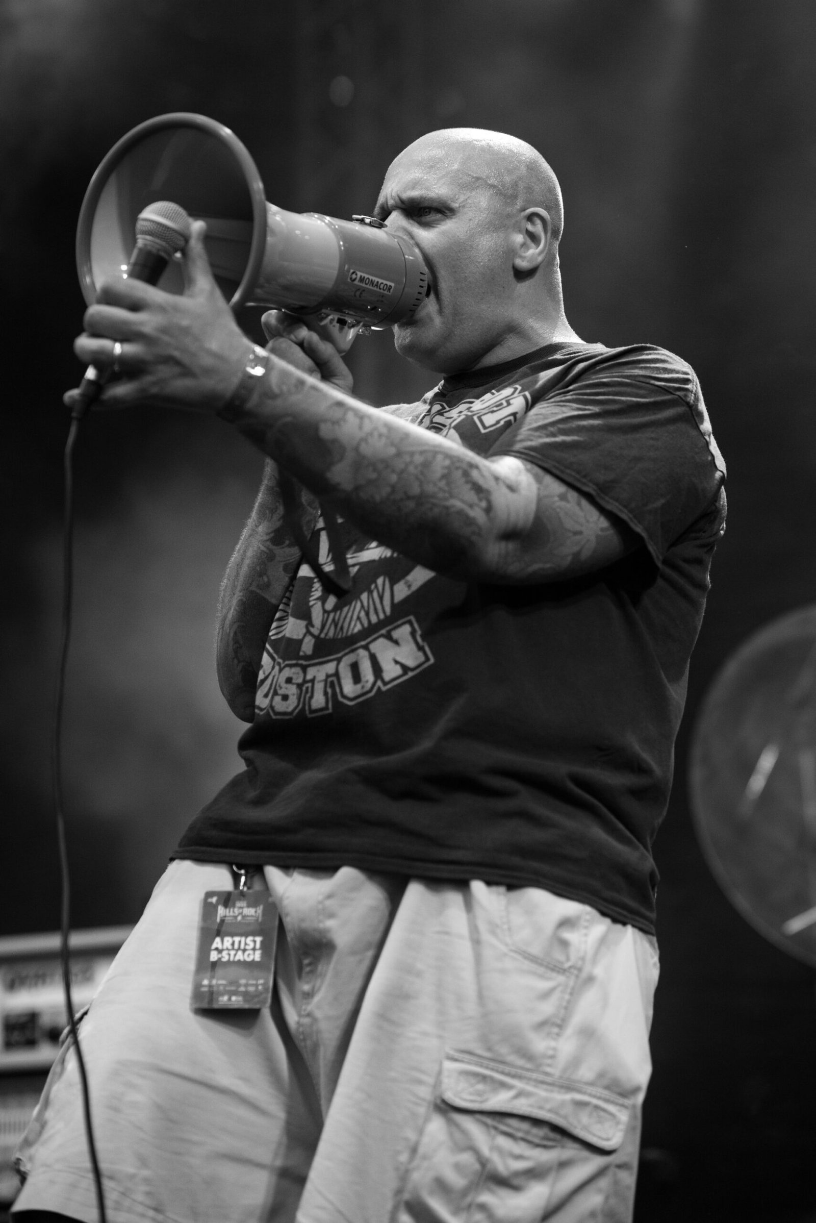 Dobromir Ganchev d'Urban Grey sur la scène d'Hills of Rock 2025, tenant un mégaphone pendant un concert.