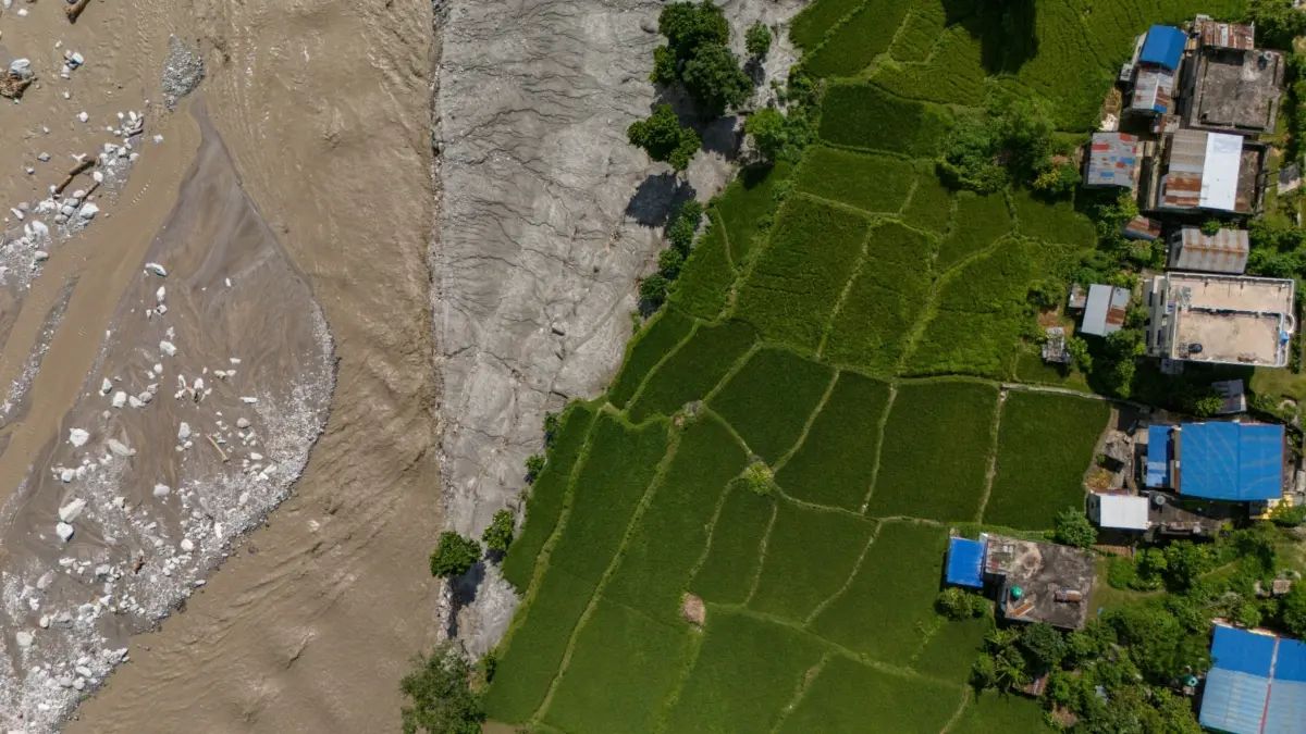 Photo showing mud on the left and houses and green earth on the left, by Suman Nepali of Nepali Times. Used with permission.