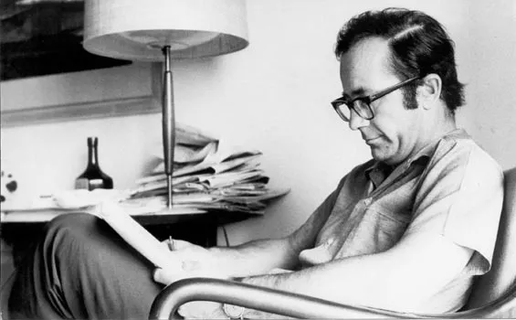 Fotografia en blanco y negro del periodista Rodolfo Walsh mientras lee un diario